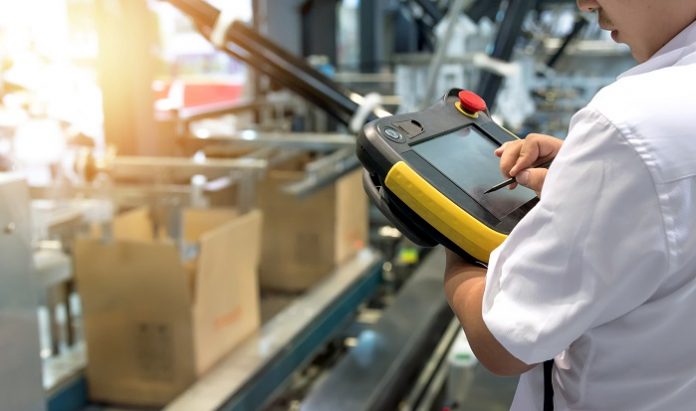 Engineer hand holding machine controller tablet to control packa